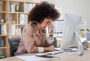 Young african american business woman looking stressed while using a computer at her desk in the office. Black woman with a headache. Mixed race woman with an afro feeling the pressure of deadlines