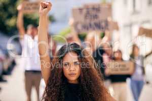 Raise your voices and make some noise. a young female protester at a rally with her fist raised.