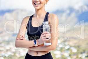 Closeup of one fit mixed race woman taking a rest break to drink water from bottle while exercising outdoors. Female athlete quenching thirst and cooling down after running and training workout