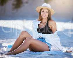 One beautiful young caucasian woman relaxing on the beach. Enjoying a summer vacation or holiday outdoors during summer. Taking time off and getting away from it all. Spending the day alone outside