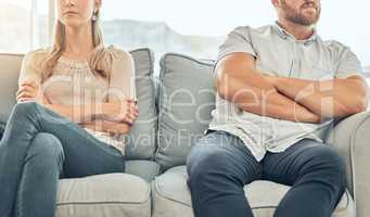 Angry caucasian married couple sitting on couch arms folded to avoid fight. Couple in conflict distanced on sofa. Frustrated couple sitting apart on a couch. Unhappy couple in therapy on sofa together