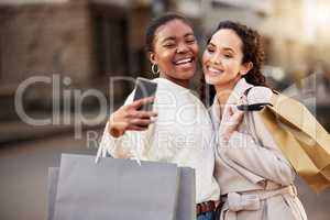 Good friends, good times, great deals. two young women taking selfies while shopping against an urban background.