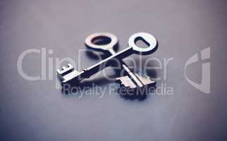 Above shot of two keys lying crossed on a table in studio. Can symbolise unlocking doors or opportunities. Could show the key to success or promotion. The key to your growth is different from the next