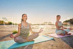 Full length yoga women meditating with legs crossed for outdoor practice in remote nature. Mixed race and caucasian mindful active people bonding and balancing for mental health. Young, serene and zen