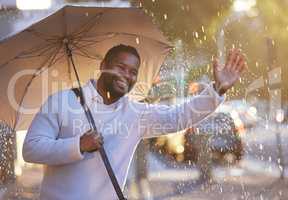 Here comes my ride, right on time. a young businessman gesturing for a cab while holding an umbrella on a rainy day in the city.