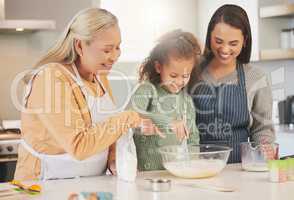 Baking is just one of the things we love doing together. a little girl baking with her mother and grandmother at home.
