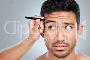 They just need a little shaping. Shot of a handsome man getting his eyebrows tweezed.