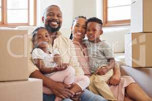Happy african american family smiling while sitting on the floor in a new home. Portrait of a young happy black couple with two children moving boxes into their new house. Black couple buying propert