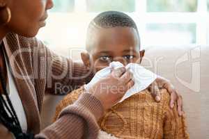 Shell nurse you back to health. a young mother helping her son blow his nose at home.