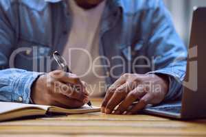 Great ideas come from within the best coffeeshops. an unrecognizable man sitting alone in a cafe and writing notes in a book.