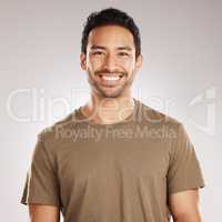 Handsome young mixed race man smiling and happy while standing in studio isolated against a grey background. Hispanic male in casual wear expressing happiness with a smile and looking at the camera