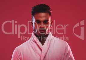 Athletic young male model wearing a bathrobe while posing posing against a red background. Handsome young hispanic man posing in the studio