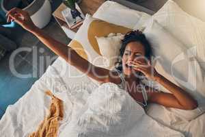 A young mixed race woman yawning and stretching while lying in bed. An attractive Hispanic female waking up from a her sleep and getting ready to begin her day