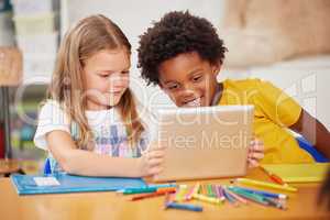 Kids love to learn. Shot of two preschool students looking at something on a digital tablet together.