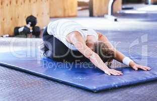 Bend and stretch to better health. Shot of a sporty young woman doing a childs pose while exercising in a gym.