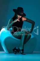 What outfit is complete without a hat. Conceptual shot of a stylish young woman posing in studio against a blue background.