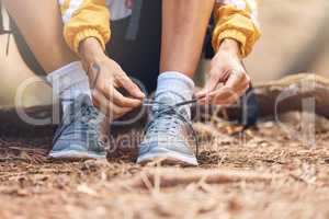 Closeup shot of an unrecognizable woman tying the laces of her sneakers while out hiking in the woods.Unknown female making sure her shoes and secure while enjoying her weekend with a hike in a forest