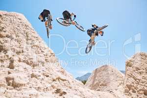 Young man showing his cycling skills while out cycling on a bicycle outside. Adrenaline junkie practicing a dirt jump outdoors. Wearing a helmet doing tricks with a bike. Extreme sports on a mountain