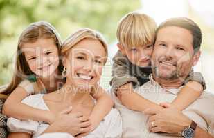 Young cheerful caucasian family enjoying relaxing time together on the weekend at home. Loving little boy and girl hugging their parents while spending time together at home