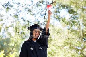 Reaping the rewards. an attractive young female graduate posing outside with her degree.