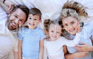 Portrait of happy carefree caucasian family in pyjamas from above lying cosy in bed at home. Loving parents spending quality time with son and daughter. Cute kids enjoy lazy morning with mom and dad
