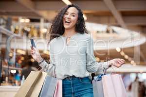 Portrait beautiful mixed race woman holding a credit card and standing in a mall shopping. Young hispanic woman carrying bags, spending money, looking for sales and getting in some good retail therapy