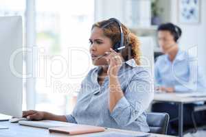 One stressed and confused mixed race call centre telemarketing agent talking on a headset while working on a computer in an office. Young shocked african american female consultant dealing with panic crisis and difficult caller for customer support