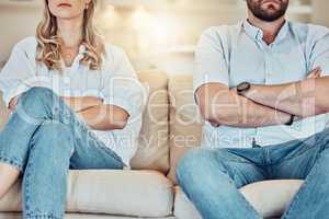 Unknown couple fighting and giving each other the silent treatment. Caucasian man and woman sitting on the sofa with their arms folded after an argument. Unhappy husband and wife ignoring each other