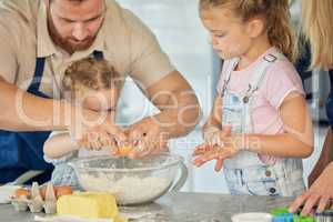 Caucasian father helping little daughter crack an egg into a bowl while baking in the kitchen at home. Family being messy and having fun while preparing ingredients for cake batter or cookie dough