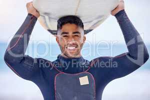 Surfing is my philosophy 101. Portrait of a handsome young man carrying a surfboard at the beach.