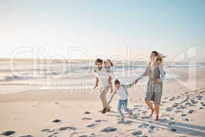 Happy parents walking with their children on the beach. Young family on vacation by the ocean. Children enjoying freedom on the beach with their parents. Loving family on a getaway together