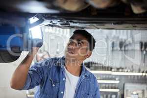 I cant believe people drive cars in this state. a handsome young male mechanic working on the engine of a car during a service.