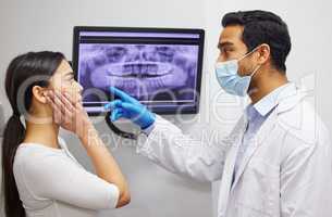 Your wisdom tooth is actually growing into your jaw bone. a dentist discussing the results of a patients teeth x ray.