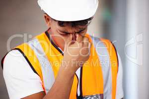 Ill need a painkiller. Shot of a young contractor suffering from a headache while working.