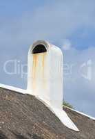 Chimney designed on the roof of a house or building outside against a cloudy sky background with copyspace. Old, dirty escape chute on rooftop exterior for fireplace or oven smoke and ventilation