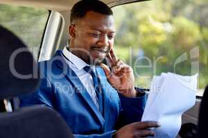 Going over the contracts. Cropped shot of a handsome businessman looking over paperwork during his morning taxi ride into work.