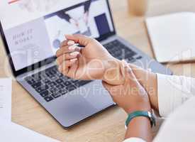 Closeup of a businessperson holding their wrist in pain while sitting at a desk at work. Business professional touching their sore arm while working in an office. Person suffering from arthritis in an office