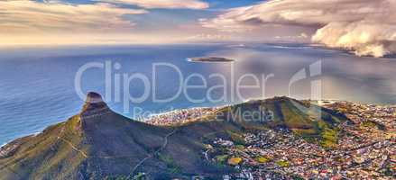 Aerial view of Lions Head mountain with the ocean and cloudy sky copy space. Beautiful landscape of green mountains with lots of vegetation surrounding an urban city in Cape Town, South Africa