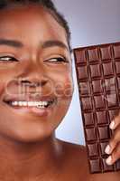 Ill tell you all about whats good for your skin and whats not. Studio shot of a beautiful young woman holding a slab of chocolate.