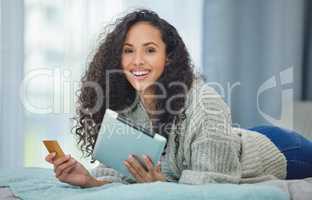 Online payments are so simple now. a young woman using her digital tablet to make online card payments.