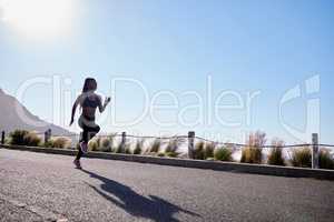 One active young african american woman running outdoors. An athlete jogging to increase cardio and endurance during a workout in the morning. Determined to reach health, fitness and wellness goals