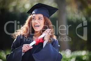 Dreaming about exciting visions of her future. a young woman holding her diploma on graduation day.