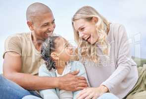 Smiling married couple bonding with daughter on the beach. Adorable little girl embracing and laughing with her mother and father outside. Happy husband and wife enjoying free time with their child