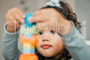 Focused and determined. Shot of a cute little girl playing with building blocks at the kitchen table.