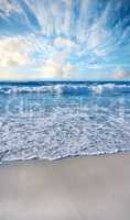 Sandy beach, sea, blue sky with clouds and copy space. Scenic seascape view of ocean waves washing on shore sand in a tropical resort with copyspace. Travel overseas, tourism abroad on summer holiday