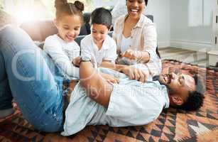 Closeup of a young hispanic family playing together on the lounge floor at home. Mixed race father and mother having fun while playing with their cute little son and daughter in the lounge at home