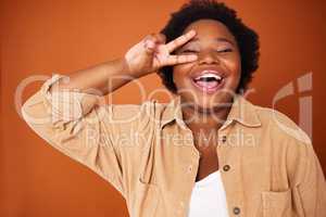 Peace, love and happiness. a young woman showing a peace sign against an orange background.