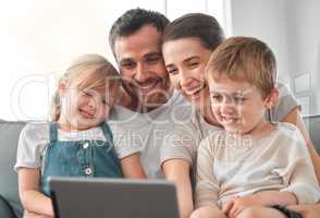 A happy home is a warm home. Shot of a young family using a digital tablet at home.