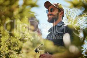 Adventurous fit man wearing glasses and a cap while out hiking or exploring the woods. Handsome man with beard smiling while exploring nature in the forest