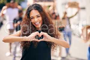 Spreading love not hate. a young female protestor forming a heart shape at a protest rally.